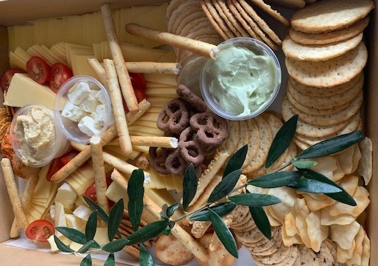 A large box containing crackers, cheeses and dips