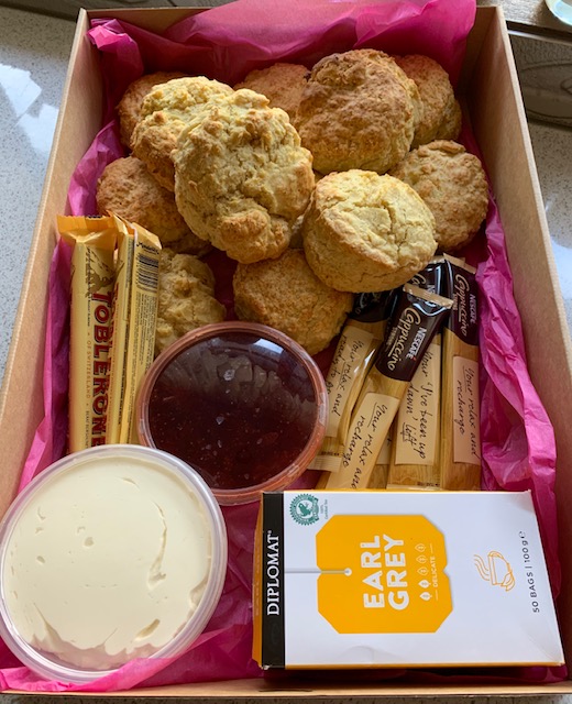 A box containing scones, jam, cream, tea, coffee and chocolate