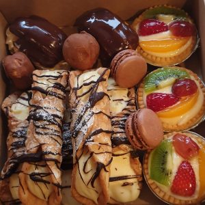 A box containing a selection of sweet treats including fruit tarts